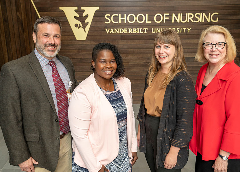 VUSN faculty in front of wood wall with VUSN logo