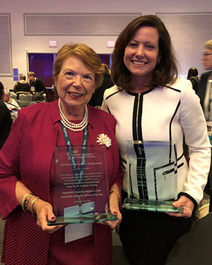 Dean Linda Norman and VUMC's April Kapu stand together holding glass engraved New Era for Academic Nursing awards
