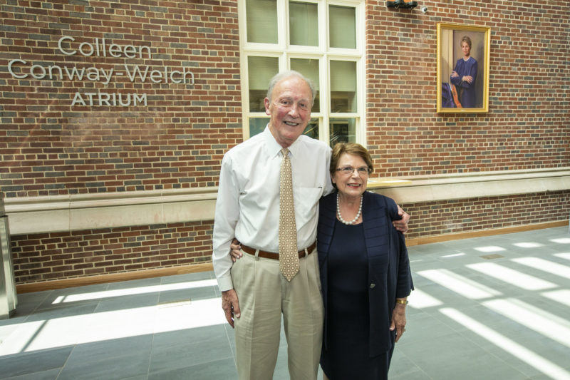 Frank Bumstead, and Dean Norman stand in front of wall in atrium with Colleen Conway-Welch portrait and name 