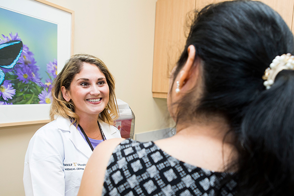 A Vanderbilt Nurse Practitioner in a white coat talks with a female patient in an exam room