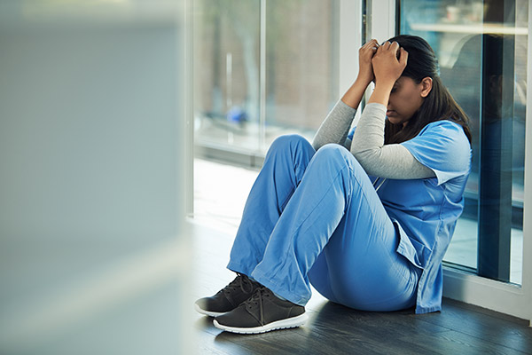 Tired nurse leaning against wall