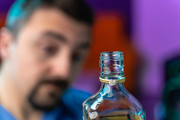 Stock image of open alcohol bottle with man in the background