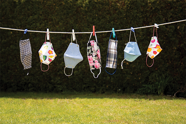 Seven cloth masks hang on a clothesline outdoors