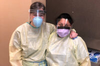Nurse practitioners gowned and wearing face masks under clear shields