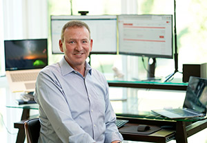 Alumnus Ken Watford sits in front of his home office setup for telehealth
