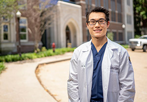 Student Jay Huang wears his white coat and stand in front of the VUSN building