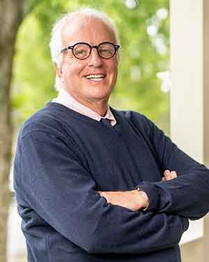 Portrait of VUSN professor Tom Christenbery leaning against porch rail.