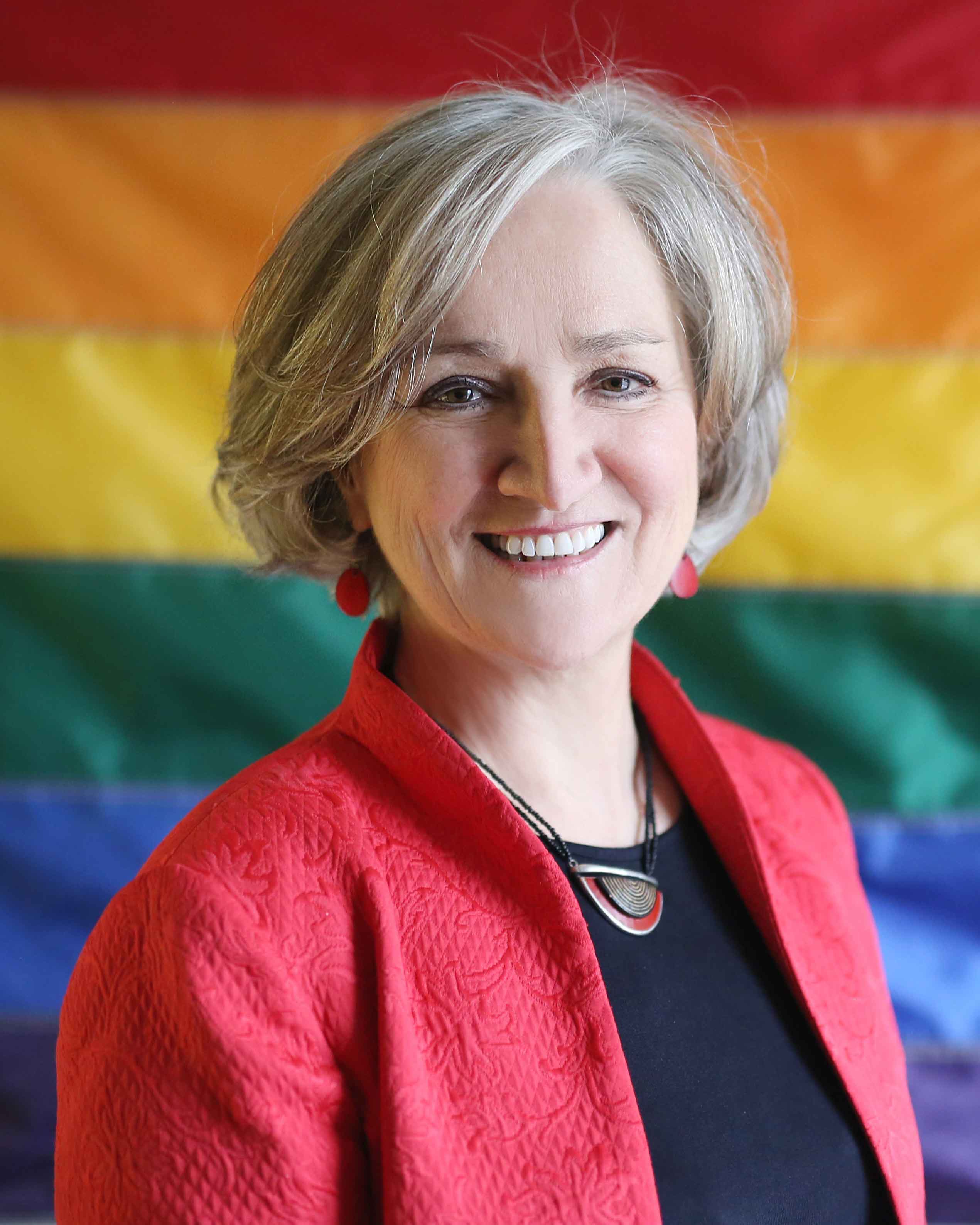 Headshot of Tonda Hughes in front of rainbow flag