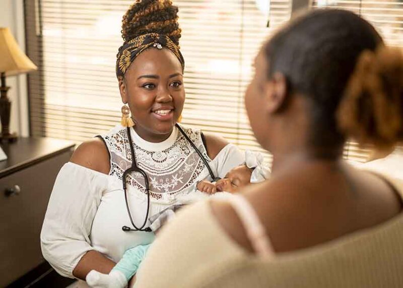 Nurse-Midwife Vernicia Winford holds her infant niece and talks to her sister-in-law