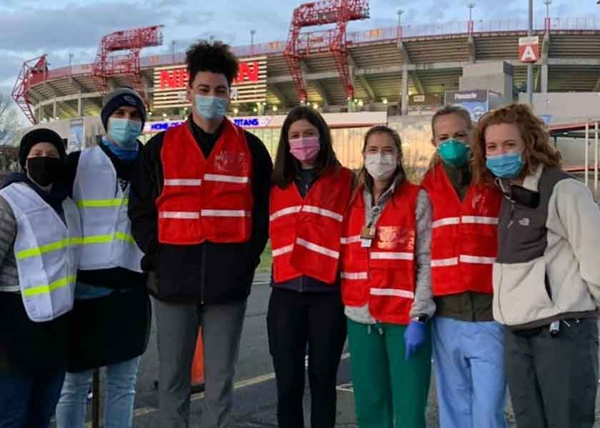 7 people in safety vests and masks stand in front of Nissan Stadium