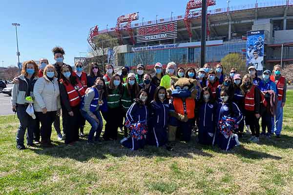 Large groups of people wearing masks and posing in front of Nissan Stadium