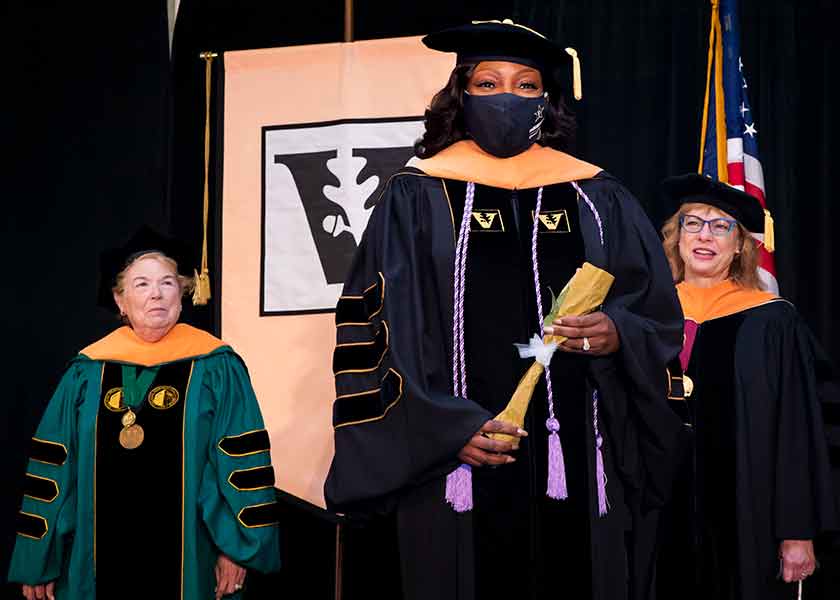 Linda Norman, graduate LaGaunda Jones, Terri Allison in academic regalia stand on stage at VUSN Commencement 2020