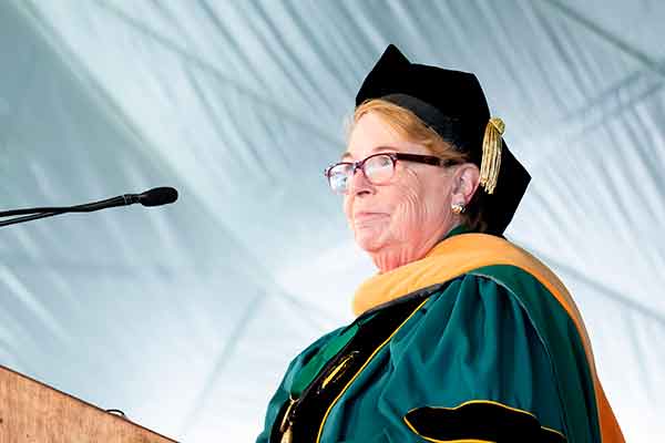 Dean Linda Norman in academic regalia at a podium