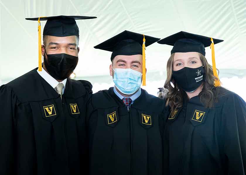 MSN graduates wearing masks and regalia. Michael Booth, Austin Rockenhaus, Ashley Allington