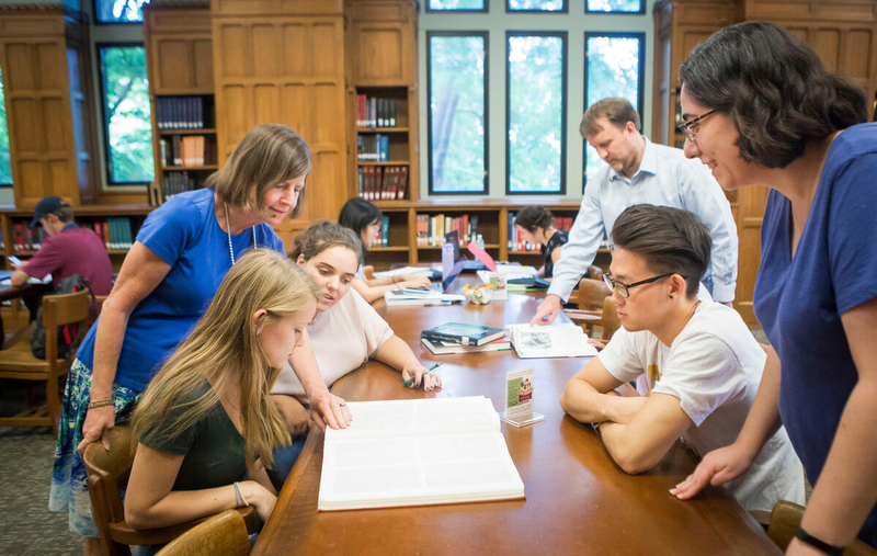 librarians assist students with projects at table in library study area