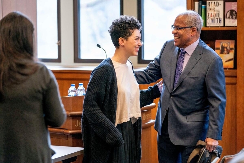 Houston Baker speaking and laughing with a student in a library meeting room