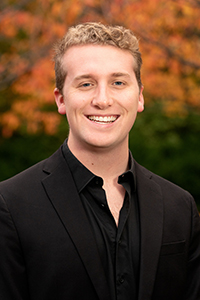 William Schmid standing outside with fall trees in background