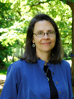 Holly McCammon, wearing a black shirt and blue jacket, stands outside on the Vanderbilt campus