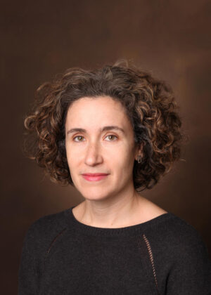 Studio photo of Allison Schachter wearing a black sweater against a brown background