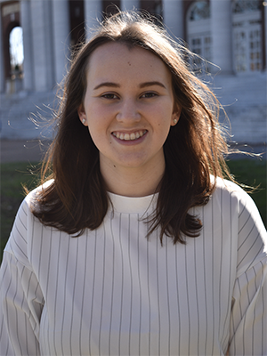 Stacy Horton, wearing a white and gray-striped sweatshirt, stands in front of a columned building