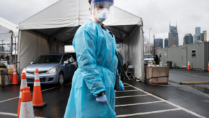 woman in PPE in front of tent