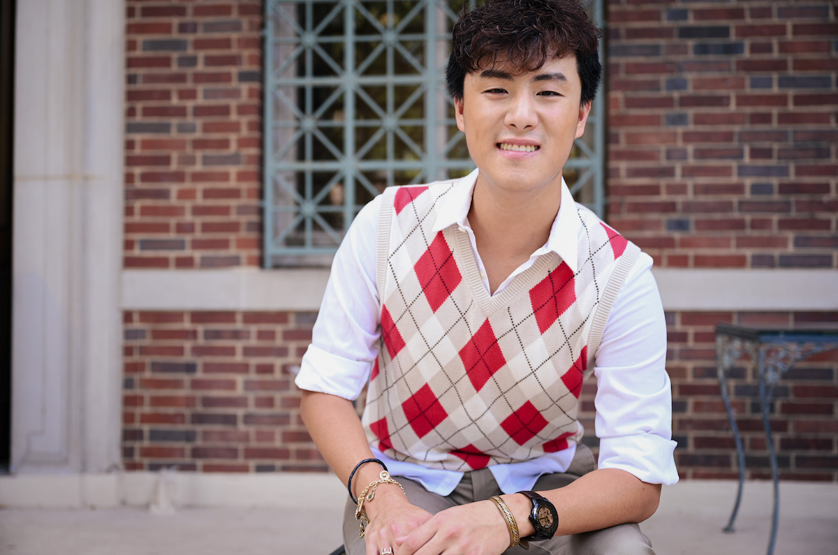 Huang sitting, smiling in front of Cohen