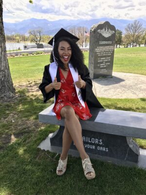 Shaniy Jarrett sitting and smiling in graduation cap & gown
