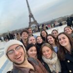 French students smiling in front of La Tour Eiffel