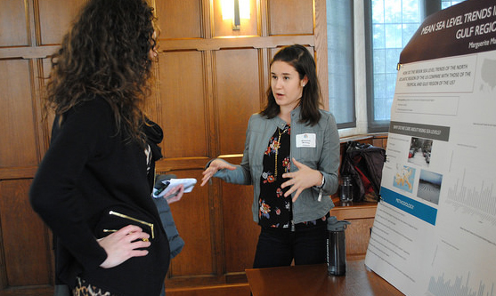 Photo of exhibit hall with participant discussing Marguerite Manning's presentation posters.