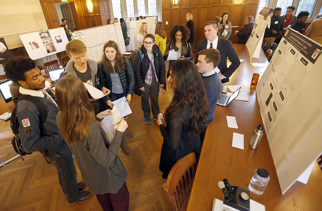 Photo of exhibit hall with participants discussing the presentation posters.