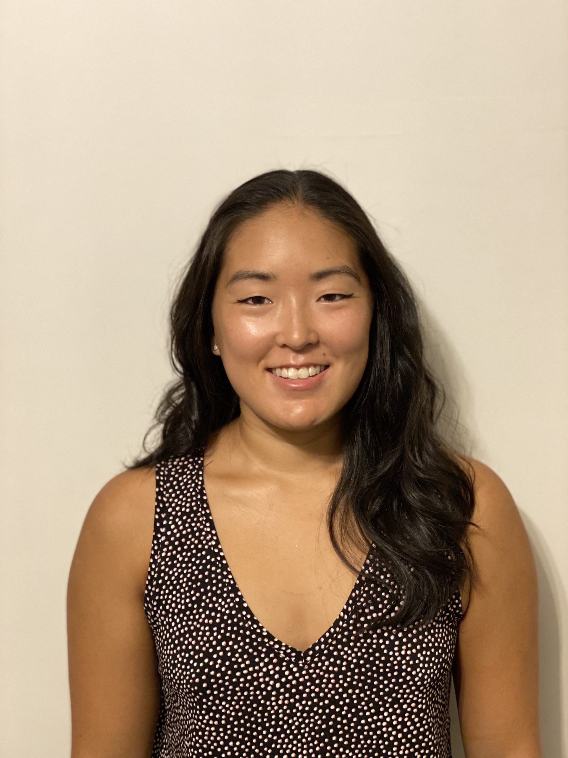 headshot of Asian woman with long hair and dark sleeveless v-neck top
